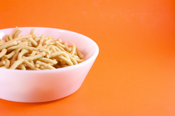 Traditional Indian Snacks on white bowl on orange background