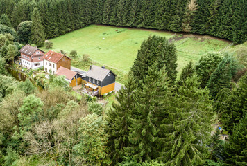 Small settlement in the Harz mountains, between a forest and a meadow for horses, aerial view