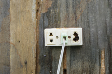 Broken thailand standard plug socket on the wood wall