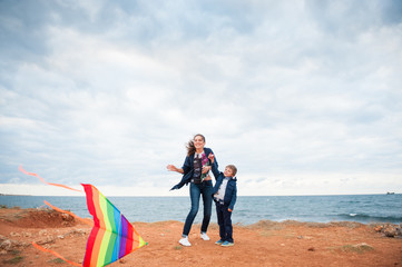 smiling mother and child playing kite outdoors near sea shore