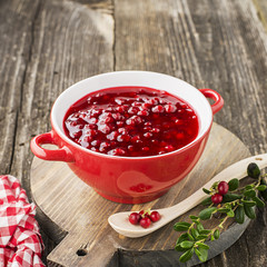 Excellent seasoning for snacks and main dishes. Fresh home made spicy sweet sauce from northern forest berries cranberries in a bowl on a background for serving to meat, to game, to cheeses. Top View.
