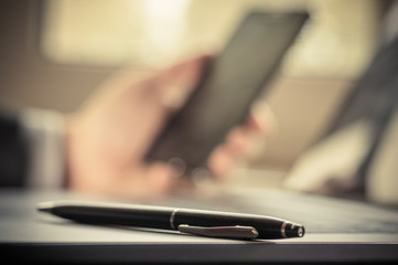 Fototapeta premium Selective focus pens lies in laptop keyboard on background businessman using a mobile phone blurry