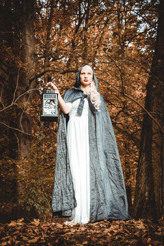 Woman with black coat and a lantern in a forest