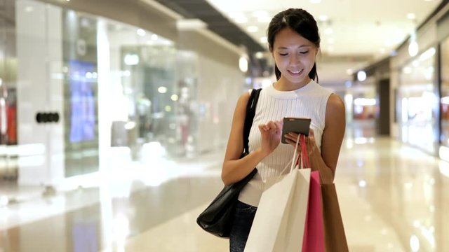 Woman use of smart phone and holding shopping bags