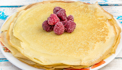 Heap of raspberry on the pile of thin pancakes.