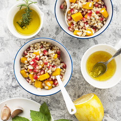 A healthy modern snack or lunch. Two bowls with pearl barley salad with slices of baked pumpkin and pomegranate seeds with butter dressing sauce. Top View.