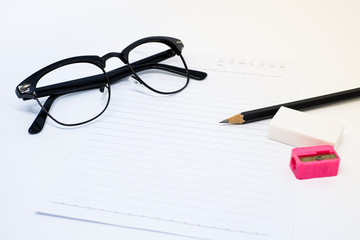 Black glasses, white paper, pencil, pink sharpener and eraser (rubber) for write your note - concept relax.