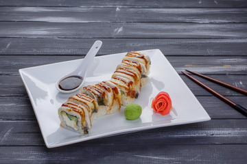 Kanada sushi rolls with salmon, eel, Philadelphia cheese, avocado and cucumber served on white flat plate with chopsticks. Asian menu for gourmets in luxury restaurant