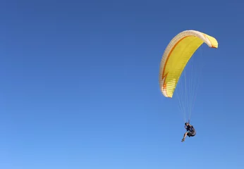 Fototapeten Man flying on a paraglider on the blue sky background © jarik2405