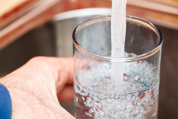 Filling up a glass with drinking water from kitchen tap
