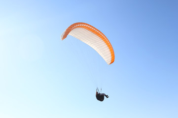 Man flying on a paraglider on the blue sky background