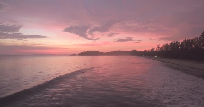 High Aerial Shot Over Tropical Beach at Sunset as Sufer Catches a Wave
