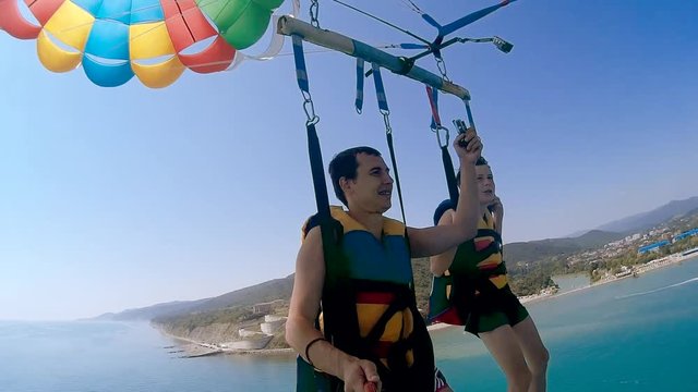 paragliding and ocean parasailing lifestyle. man and boy are flying on a parachute over the sea. Extreme sport first-person view