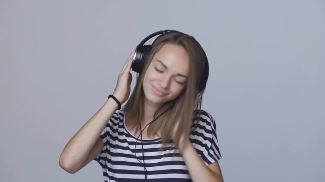 Teen girl listening to music in headphones and dancing, enjoing with closed eyes