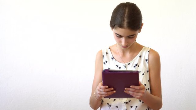 Beautiful girl with tablet computer sits on the bench in summerhouse. Girl playing the game on his tablet computer. Little girl with Tablet-PC sits on the bench in bower