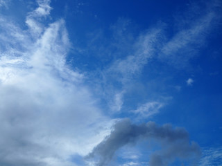 Obraz premium Bright clear gradient blue sky background with gradient chunk of white grey dark cloud from lower left corner