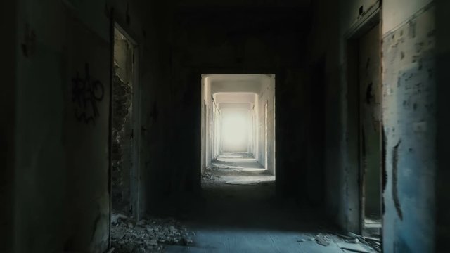 Backtracking drone dolly shot inside a long corridor/hallway of a destroyed by an earthquake and evacuated building.