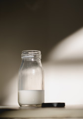 Open traditional glass milk bottle on table in low light