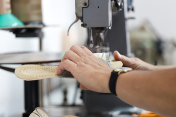Female shoemaker sewign flip flops on dedicated machine