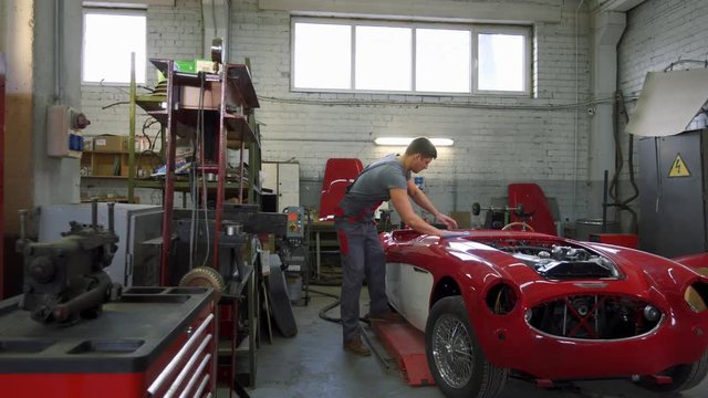Mechanic polishning car in restoration workshop