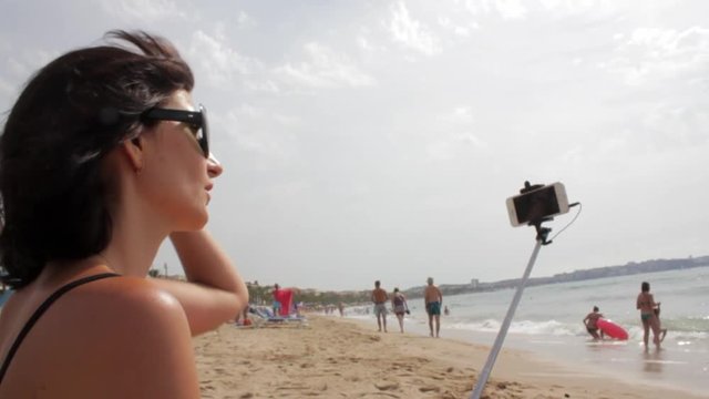 Girl Use Selfie Stick To Take Photos on sea beach