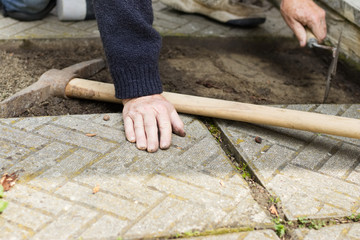 Repair of the tile pavement. Installation of paving slabs. Man prepares the surface of the ground for laying tiles. 