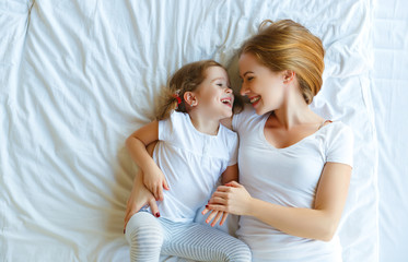  Happy family mother and child daughter laugh in bed