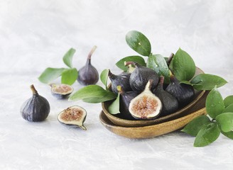 dark blue Fresh figs in a wooden bowl on a white marble table, selective focus