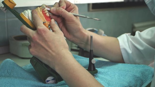 Dental technician removes excess wax from denture with a scalpel