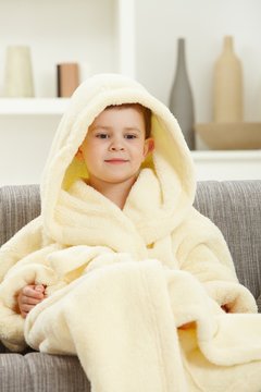Portrait of smiling little boy in bathrobe at home