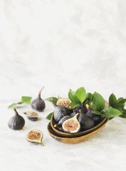 dark blue Fresh figs in a wooden bowl on a white marble table, selective focus