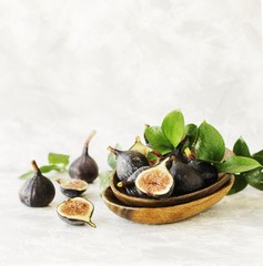 dark blue Fresh figs in a wooden bowl on a white marble table, selective focus