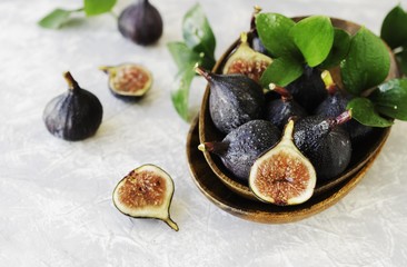dark blue Fresh figs in a wooden bowl on a white marble table, selective focus