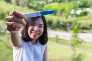 a short hair young woman smiling and showing the pregnancy test