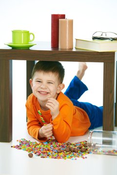 Smiling boy with sweets under table at home indoor