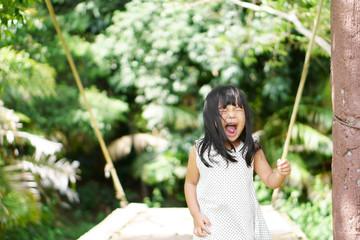 Naklejka premium Asian children cute or kid girl open mouth with scared and crying because afraid of height on the bridge and nature with space for crop or add text
