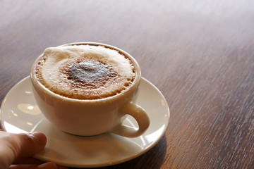 serve fresh hot cappuccino coffee in white cup on wood table in the morning for breakfast drink before work on warm white and nature light at cafe restaurant or office