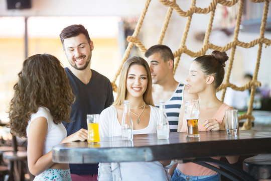 Group of friends talking and drinking at bar