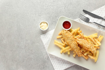Plate with tasty fried fish and chips on table