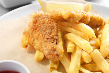 Tasty fried fish and chips on plate, closeup