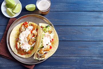 Plate with tasty fish tacos on wooden table