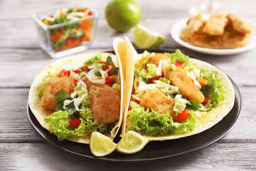 Plate with tasty fish tacos on wooden table