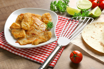 Plate with fried fish fillet for tacos on wooden table