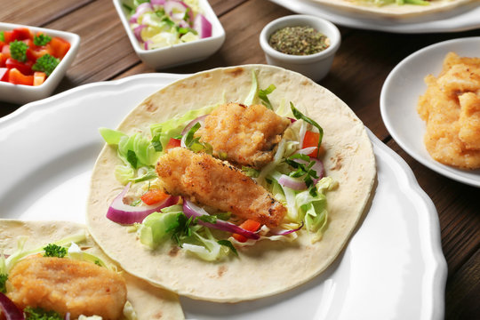 Plate with fish tacos on wooden table