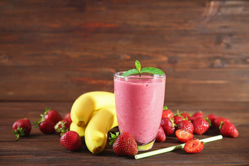 Glass of fresh strawberry and banana smoothie on wooden table