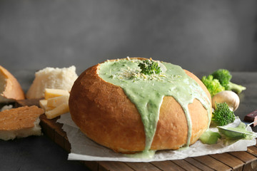 Delicious broccoli cheese soup in bread on table