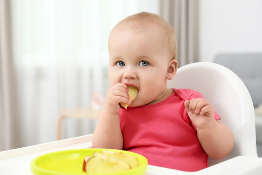 Little baby eating apple indoors
