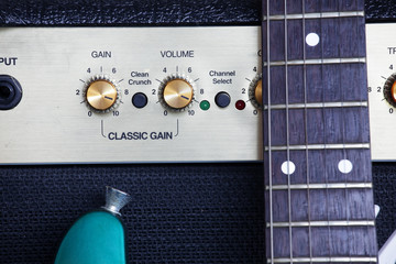 close up of guitar fingerboard with guitar amplifier background.