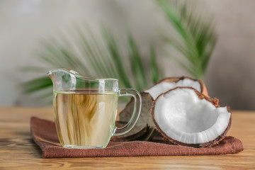 Ripe coconut and pitcher with oil on wooden table