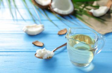 Pitcher with coconut oil on color wooden background